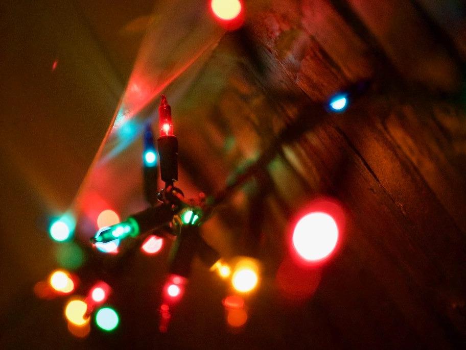 A string of multi-colored Christmas lights against a wooden surface